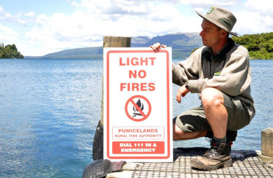 Ranger with light no fires sign at Lake Tarawera. 