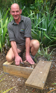 DOC Conservation Ranger, Evan Smith, setting a stoat trap.