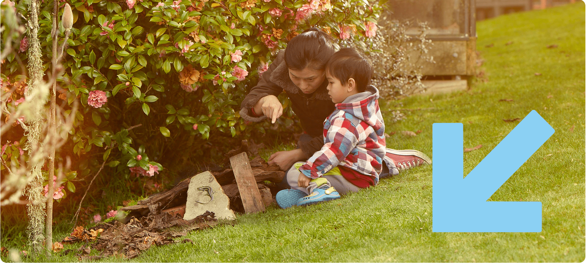 Mum and child in the backyard looking at a gecko.