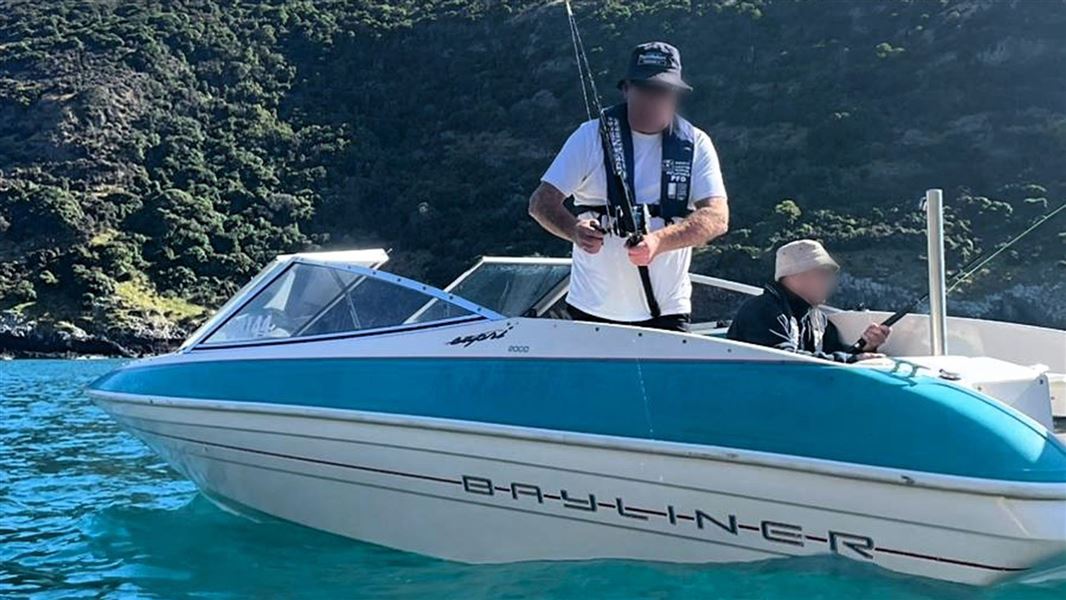 Two men, with faces blurred, fish from a small boat.