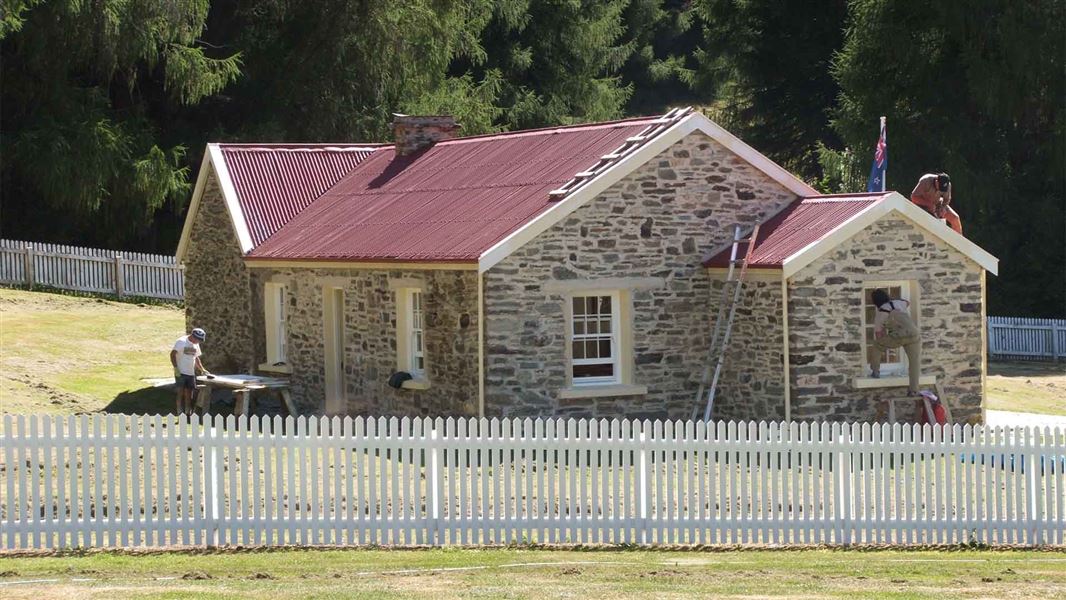 People working on a small stone building.
