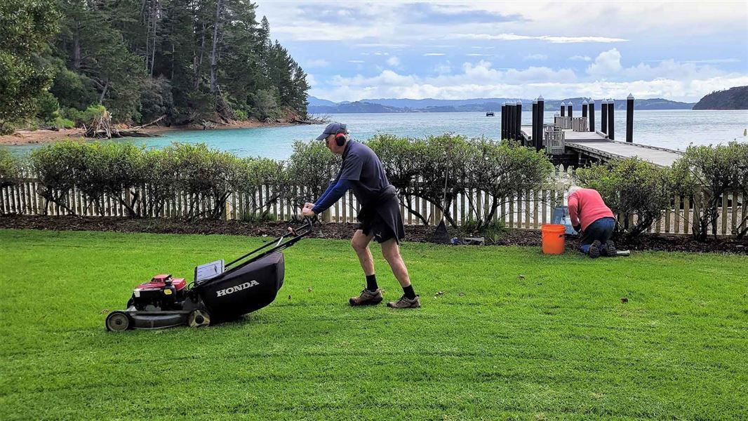 Two people working in the gardens with a view of the bay.