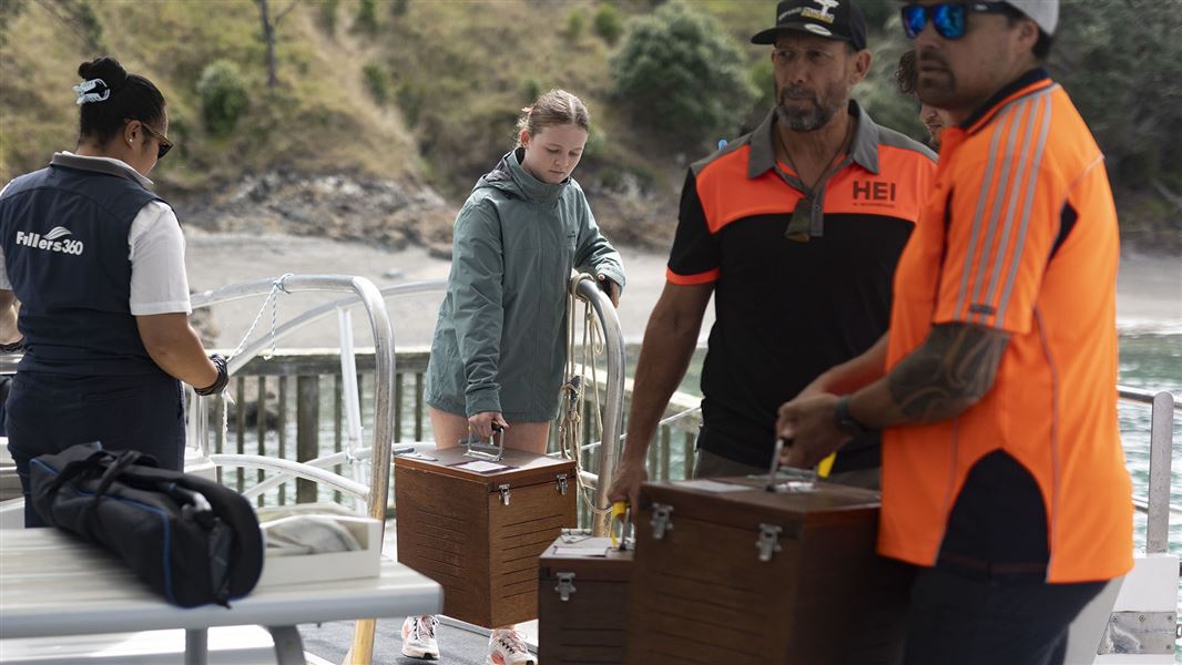 People carry boxes on to a boat.