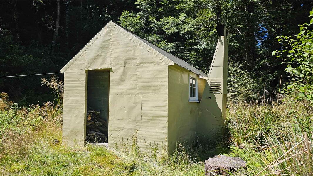 Close up of a small beige hut with a chimney. 