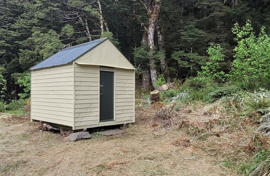 A small beige hut with a maroon front door. 