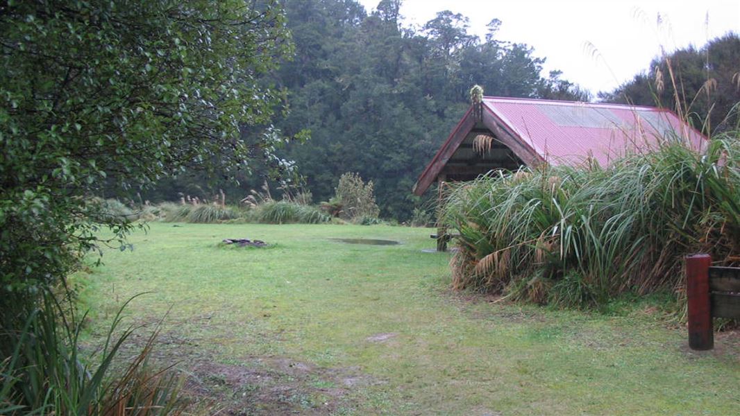 Grassy camping area with a shelter in the background.