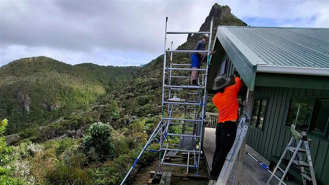 scaffolding against a hut with people working on it. 