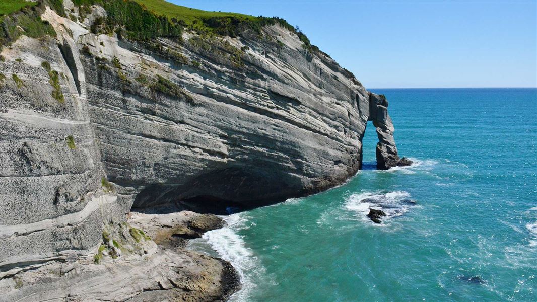 Dramatic light grey stone cliffs meet the ocean.