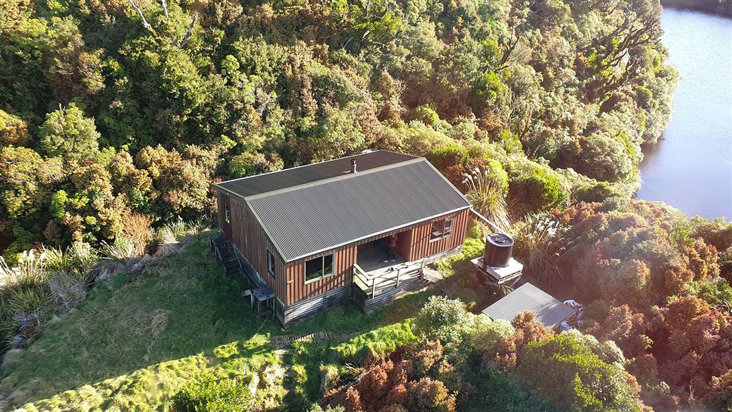 Small wooden building surrounded by bush.