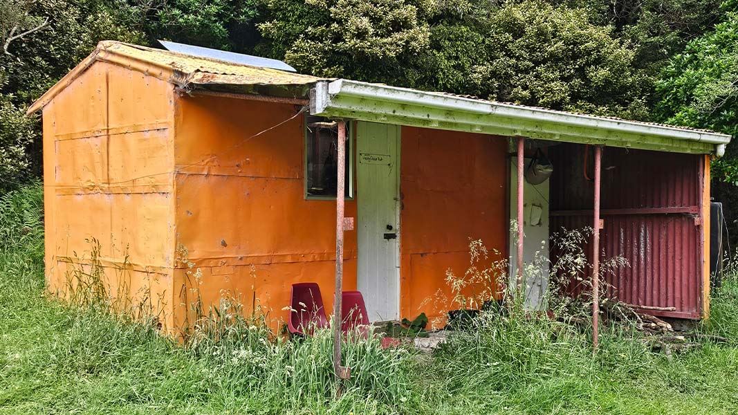 A rustic looking hut that is painted bright orange.