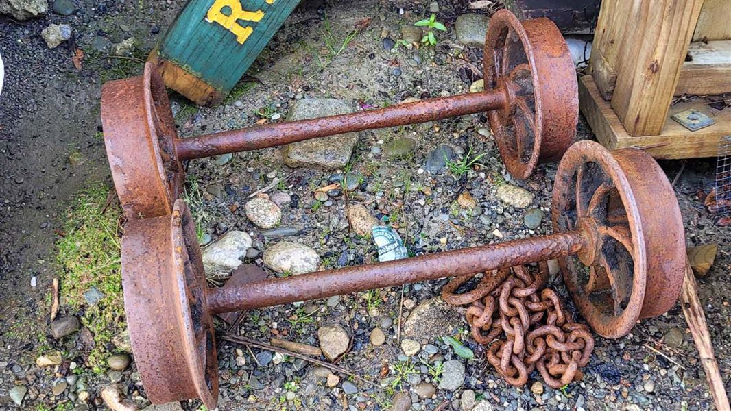 Two rusty old axles with wheels attached.