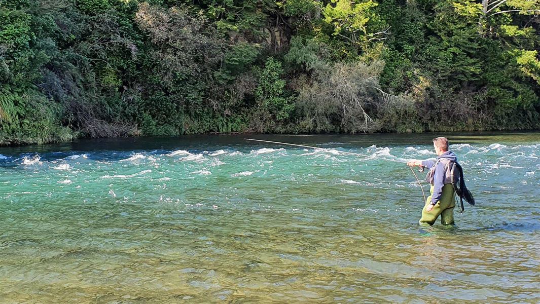 A man standing in a river fly fishing.