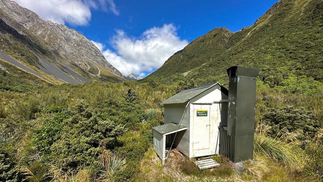 Small hut in valley between two tall ranges.