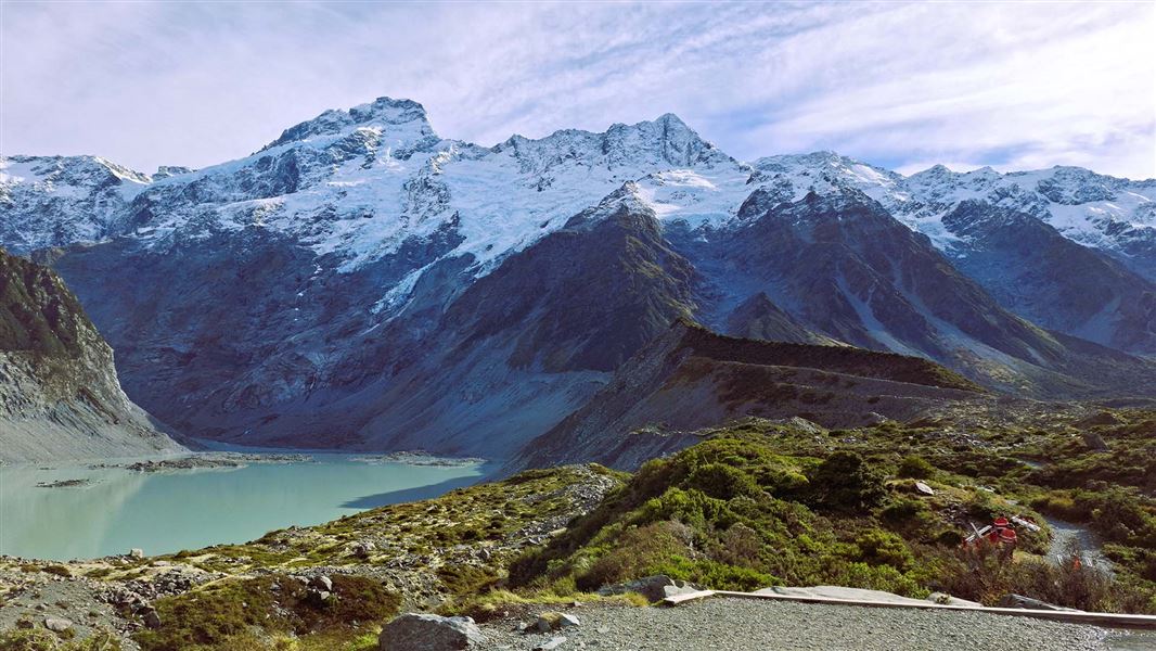 View of across a valley and river with mountain range in the background.