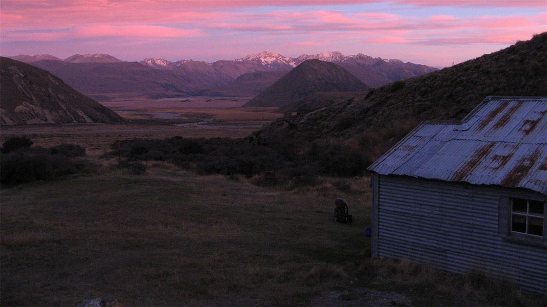 Early morning view over a river plain with snowcapped mountains in the distance.