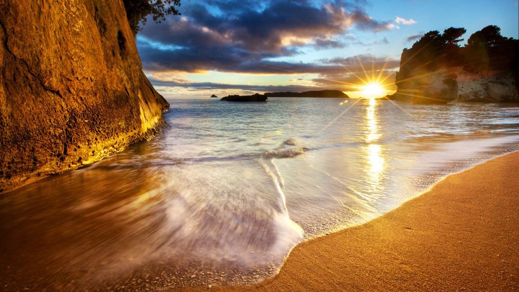 A close up of the tide ebbing from the beach at sunset.
