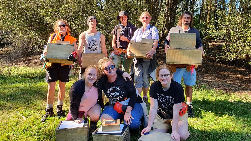 Trap training group stands in the sun smiling and holding traps