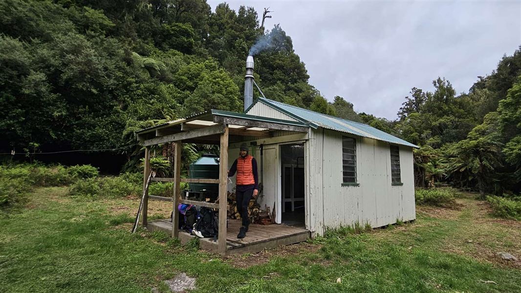 A woman stands on the deck of Tawa Hut. 