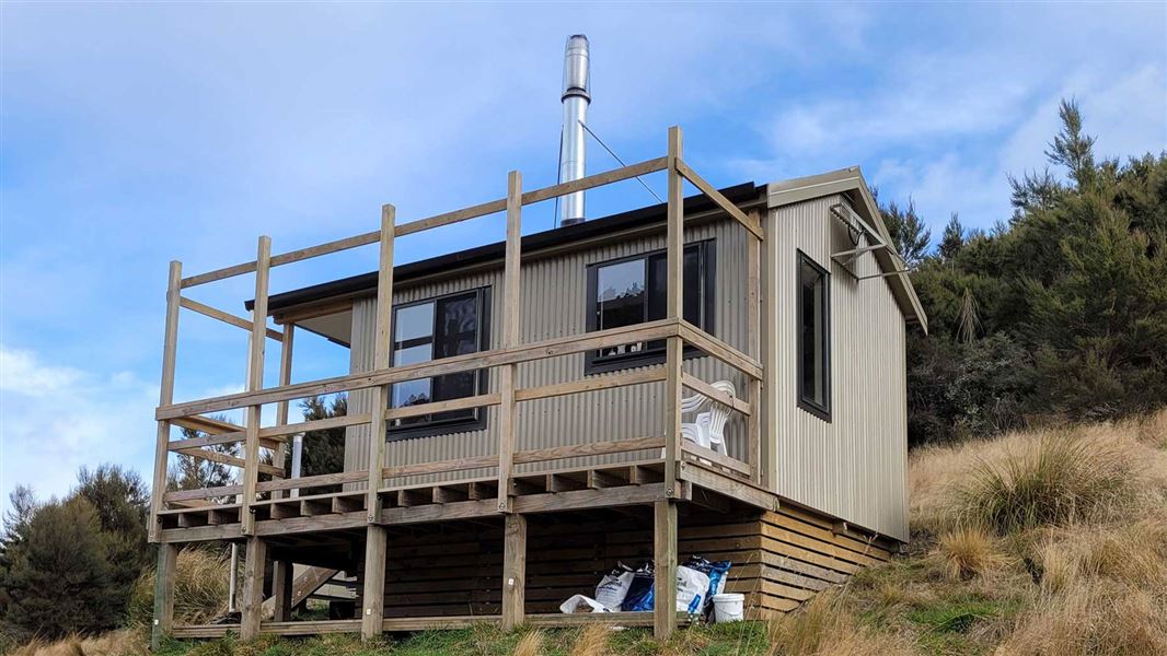 Small hut with balcony on a grassy hillside.