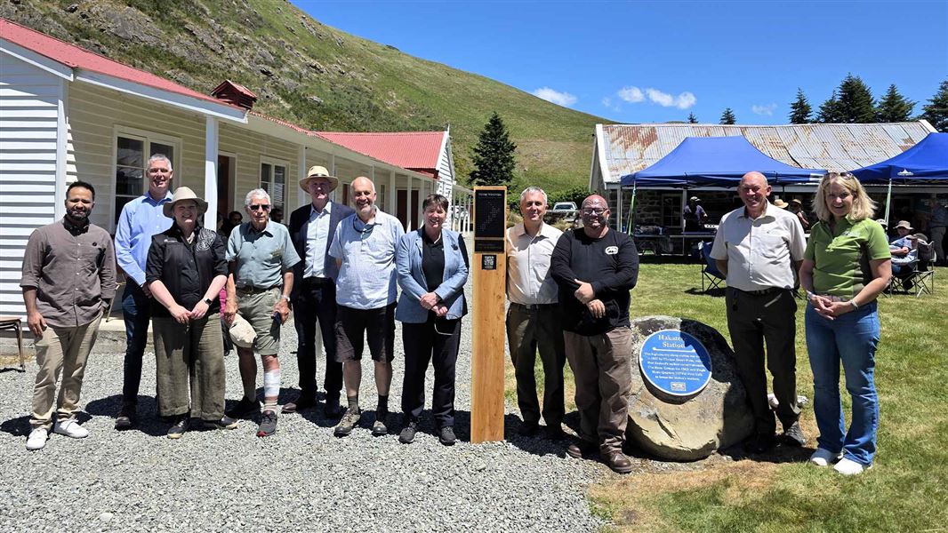 11 people pose in front of a white heritage building. 