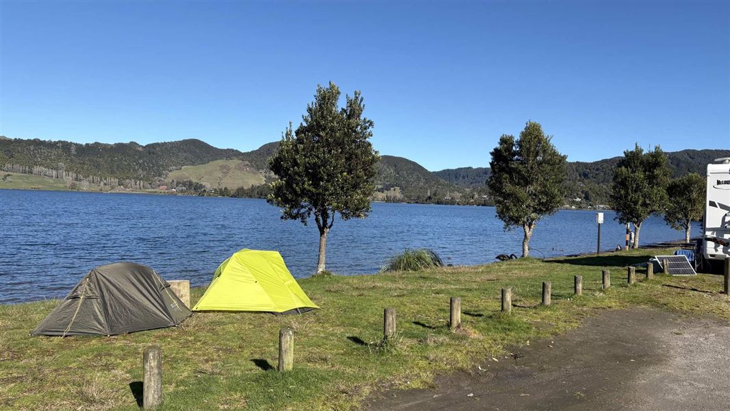 2 tents and a campervan at a campsite on the lake edge.