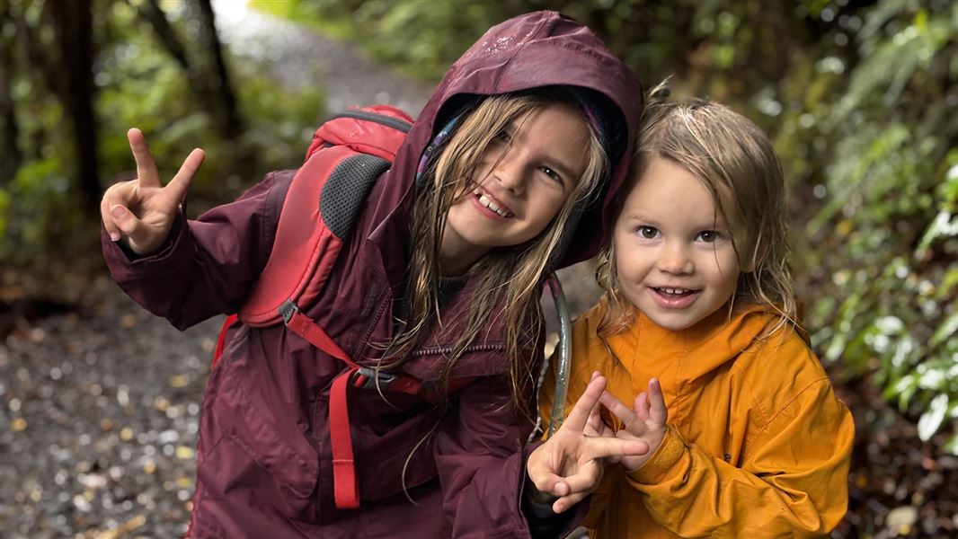 Two smiling children stand on a walking track.