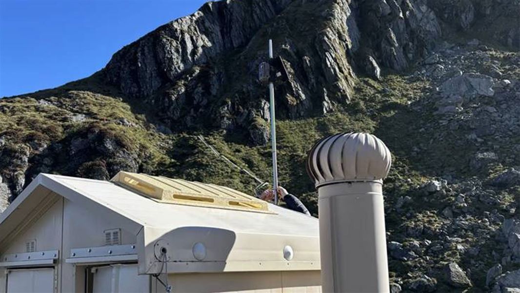 Toilet sensor relay device being mounted on pole behind the toilet block at Harris Shelter on Harris Saddle. 