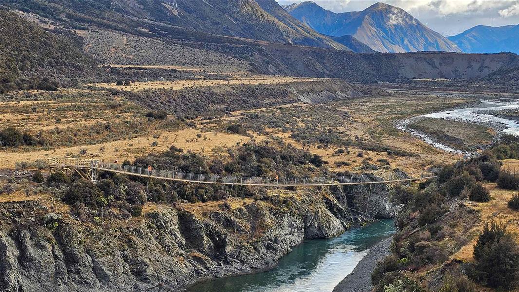 McArthur swingbridge spanning over a turquoise river in a wheat coloured valley. 