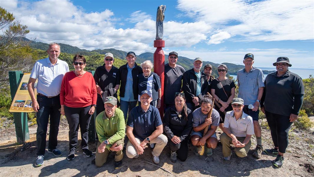 Annette Plowman (fifth from left, top row) and her son Peter (second from left, bottom row) alongside representatives from Project Janszoon, the NEXT Foundation, the Department of Conservation, Abel Tasman Birdsong Trust, Ngāti Rārua, Ngāti Tama and Te Ātiawa, at the unveiling of a seat, signage and wheku acknowledging the Plowmans’ contribution to Abel Tasman National Park. 