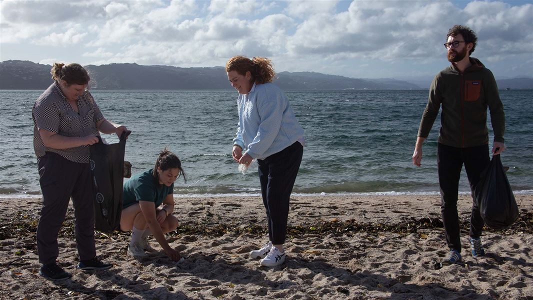 A group of people picking up rubbish on a sandy beach.