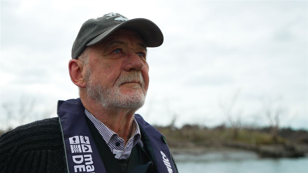 Close up of an older man wearing a life jacket against a river background.