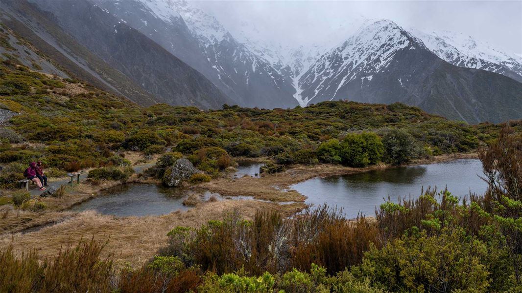 Hikers take a break on a bench seat at Red Tarns.