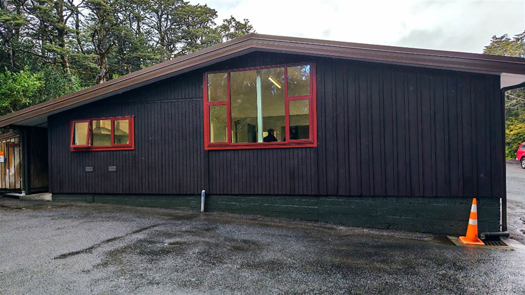 A timber building, freshly painted in black with red joinery.
