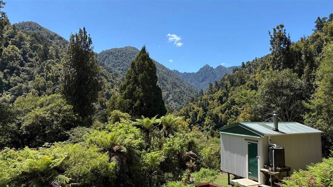 Well-maintained looking hut in a wooded hills setting.