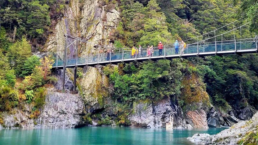 Suspension bridge across a calm blue coloured river.