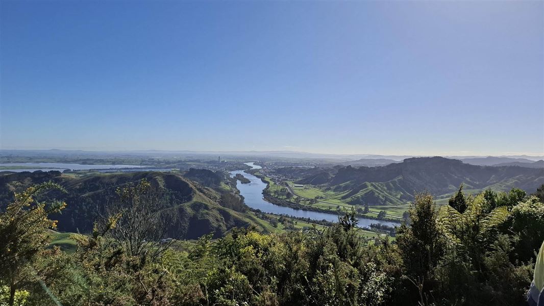 View from on high down to river nestled among green hills with a two on the banks.