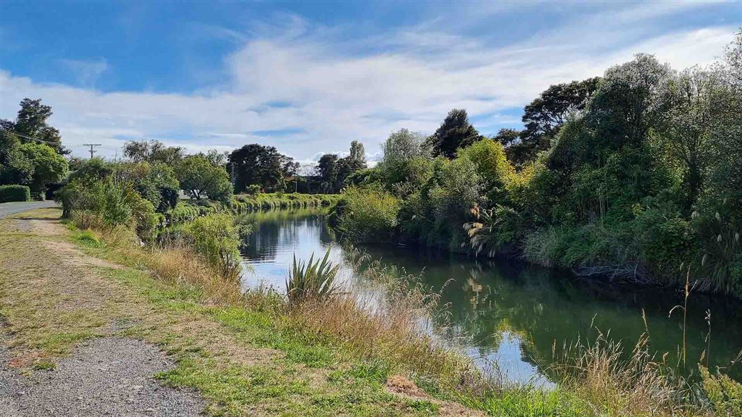A river that running beside a gravel road.